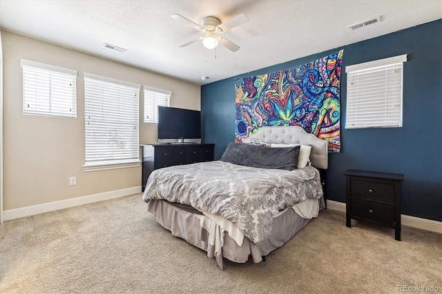 carpeted bedroom with ceiling fan and a textured ceiling