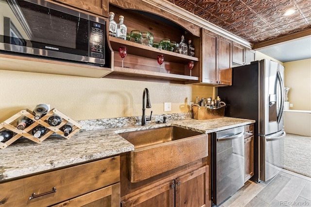 kitchen featuring light stone countertops, light hardwood / wood-style flooring, stainless steel appliances, and sink