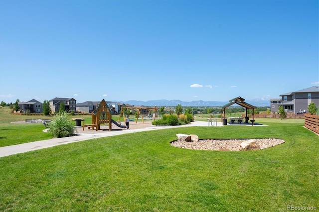 view of property's community featuring a playground, a mountain view, and a yard