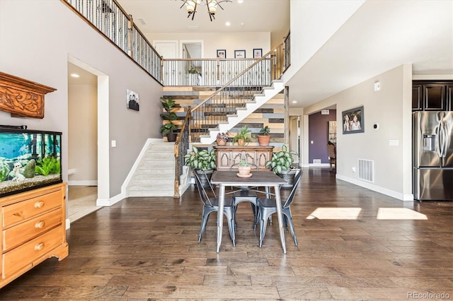 dining space with dark hardwood / wood-style floors, a high ceiling, and a notable chandelier