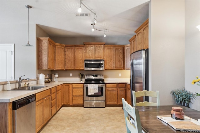 10818 Cimarron St Unit 1102, Firestone, CO 80504 - kitchen featuring appliances with stainless steel finishes, light countertops, brown cabinetry, and decorative light fixtures