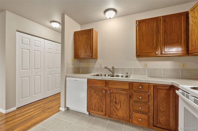kitchen with white appliances, a sink, and brown cabinets