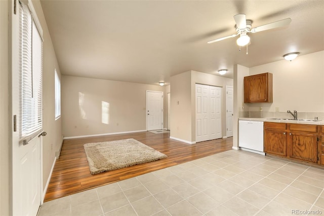 kitchen featuring brown cabinets, light wood finished floors, light countertops, a sink, and white dishwasher