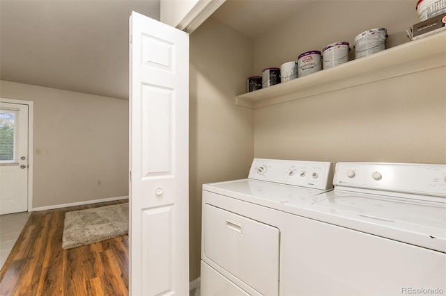 clothes washing area with washing machine and dryer, wood finished floors, and laundry area