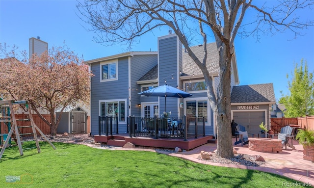 14533 W 69th Pl, Arvada, CO 80004 - rear view of property featuring a deck, an outdoor fire pit, a playground, an attached garage, and a chimney