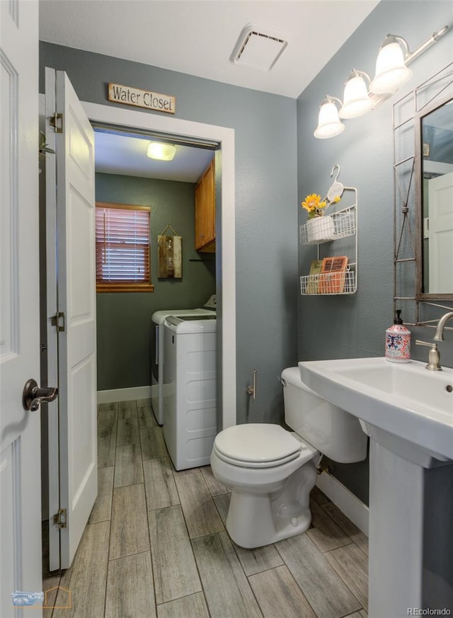 14533 W 69th Pl, Arvada, CO 80004 - half bath featuring washing machine and clothes dryer, wood tiled floors, toilet, and baseboards