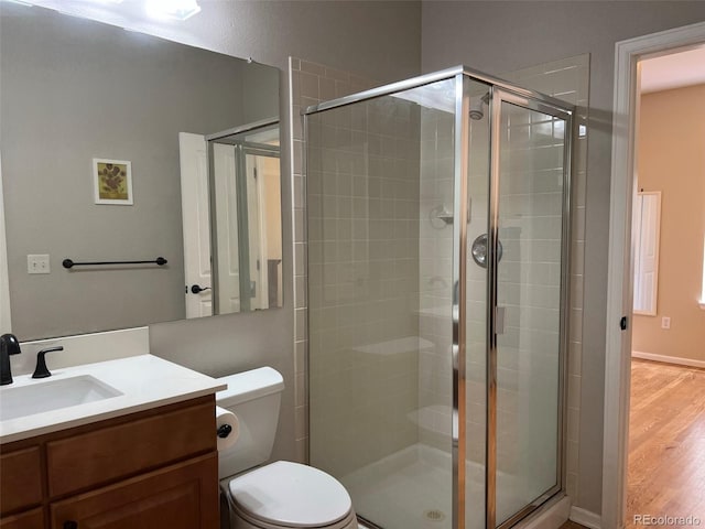 bathroom featuring hardwood / wood-style flooring, vanity, a shower with door, and toilet