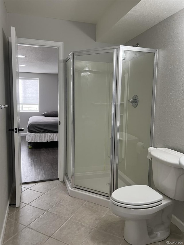 bathroom with walk in shower, toilet, and tile patterned floors