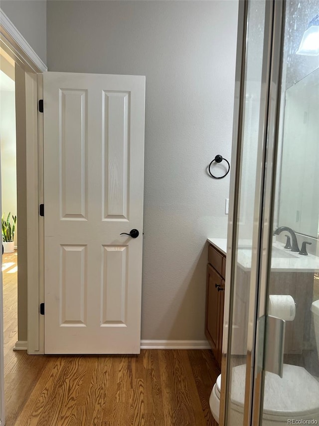 bathroom with an enclosed shower, hardwood / wood-style flooring, vanity, and toilet