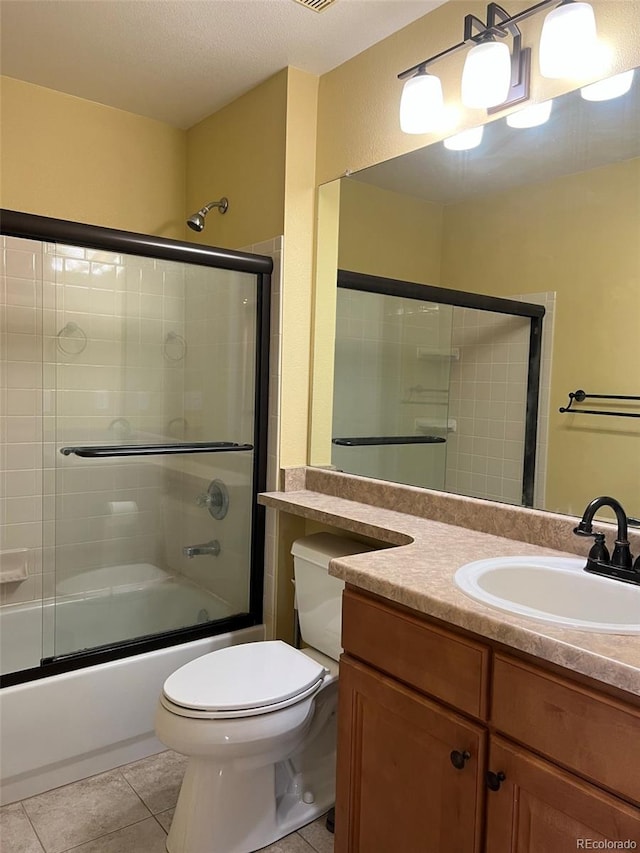 full bathroom featuring vanity, tile patterned floors, combined bath / shower with glass door, toilet, and a textured ceiling