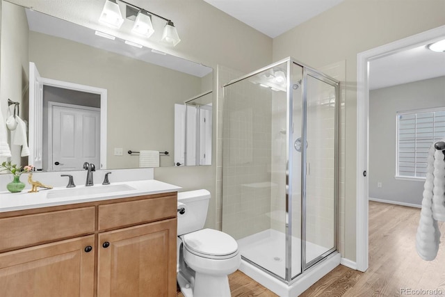 bathroom featuring hardwood / wood-style flooring, vanity, toilet, and a shower with shower door