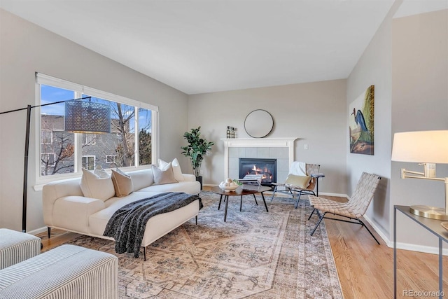 living room with a tiled fireplace and hardwood / wood-style flooring