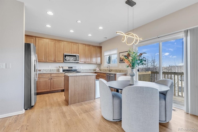 kitchen with decorative light fixtures, light hardwood / wood-style flooring, stainless steel appliances, and a kitchen island