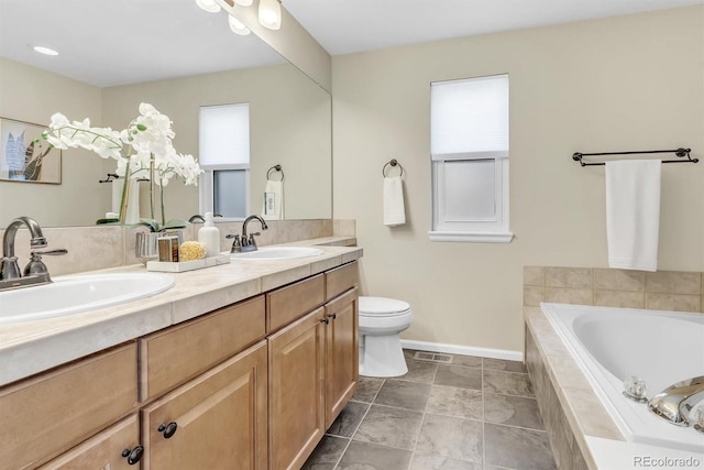 bathroom with vanity, a relaxing tiled tub, and toilet