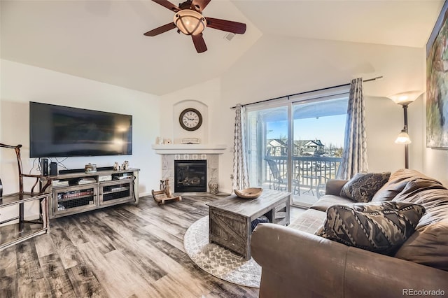 living area featuring lofted ceiling, ceiling fan, a fireplace, and wood finished floors