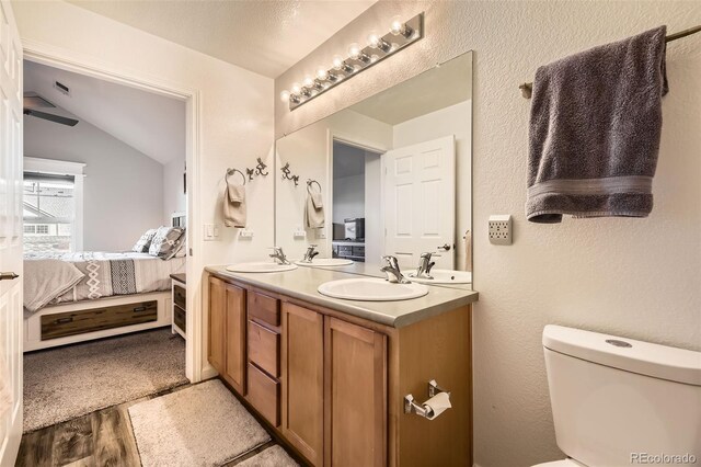 ensuite bathroom with ensuite bathroom, double vanity, wood finished floors, and a sink