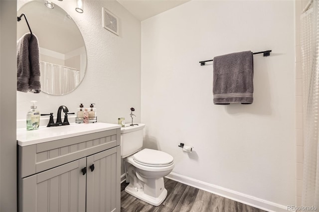 full bathroom with visible vents, toilet, vanity, wood finished floors, and baseboards