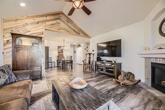 living room featuring ceiling fan, high vaulted ceiling, a fireplace, and wood finished floors