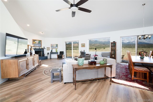 11865 Rangeview Cir, Salida, CO 81201 - living room with a fireplace with raised hearth, a chandelier, light wood finished floors, ceiling fan, and plenty of natural light