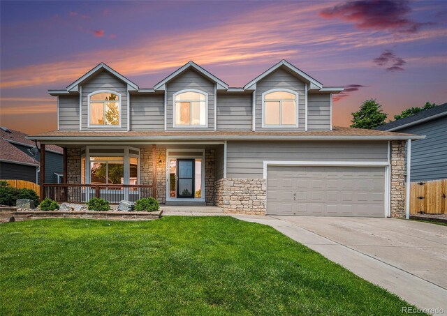 5573 S Taft St, Littleton, CO 80127 - traditional home with a porch, driveway, stone siding, and a garage