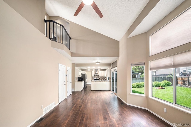 5573 S Taft St, Littleton, CO 80127 - unfurnished living room featuring ceiling fan, high vaulted ceiling, dark wood-style floors, baseboards, and a textured ceiling