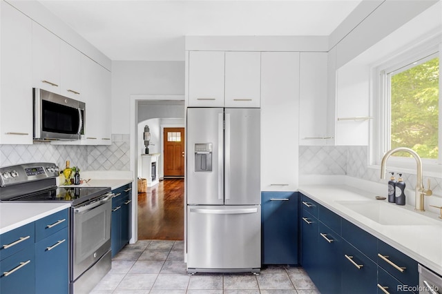 4421 Raleigh St, Denver, CO 80212 - kitchen featuring stainless steel appliances, blue cabinetry, white cabinets, and healthy amount of natural light