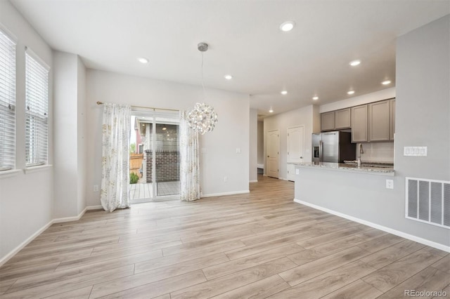 3831 E 141st Ave, Thornton, CO 80602 - unfurnished living room featuring a chandelier, light wood-style floors, recessed lighting, baseboards, and a sink