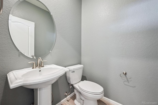 3831 E 141st Ave, Thornton, CO 80602 - bathroom with wood finished floors, toilet, a sink, and a textured wall