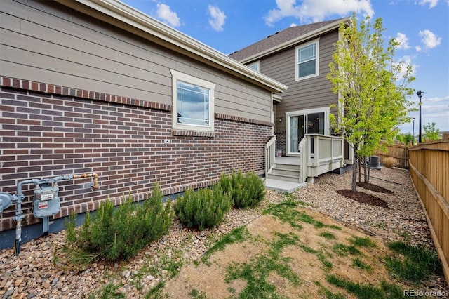 3831 E 141st Ave, Thornton, CO 80602 - view of side of property with a fenced backyard, a wooden deck, brick siding, and central AC
