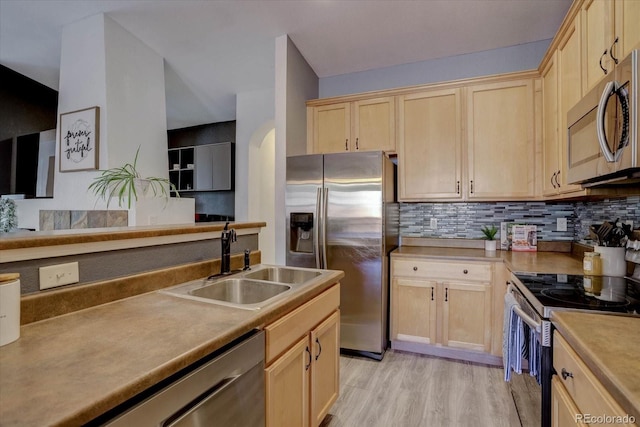 kitchen featuring appliances with stainless steel finishes, tasteful backsplash, sink, light hardwood / wood-style floors, and light brown cabinets