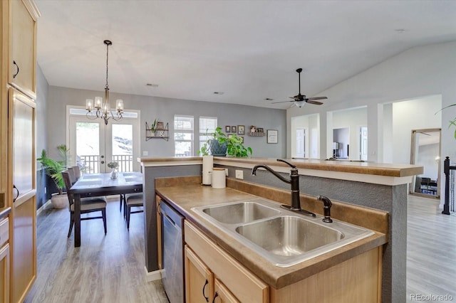 kitchen with sink, decorative light fixtures, light wood-type flooring, stainless steel dishwasher, and a kitchen island with sink