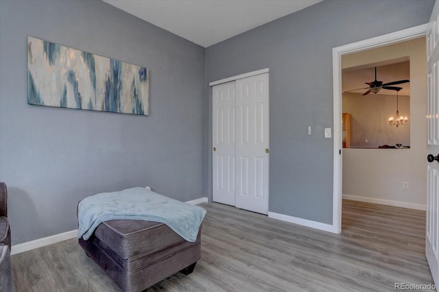 living area featuring ceiling fan with notable chandelier and light wood-type flooring