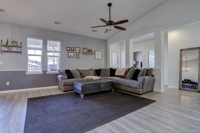 living room featuring ceiling fan with notable chandelier, light hardwood / wood-style flooring, and high vaulted ceiling