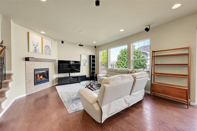 living room featuring a tile fireplace, dark hardwood / wood-style floors, and a textured ceiling