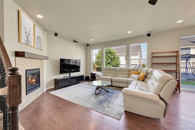 living room with wood-type flooring and a tiled fireplace