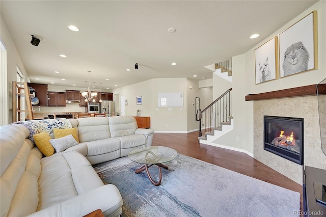 living room with a notable chandelier, wood-type flooring, and a tiled fireplace