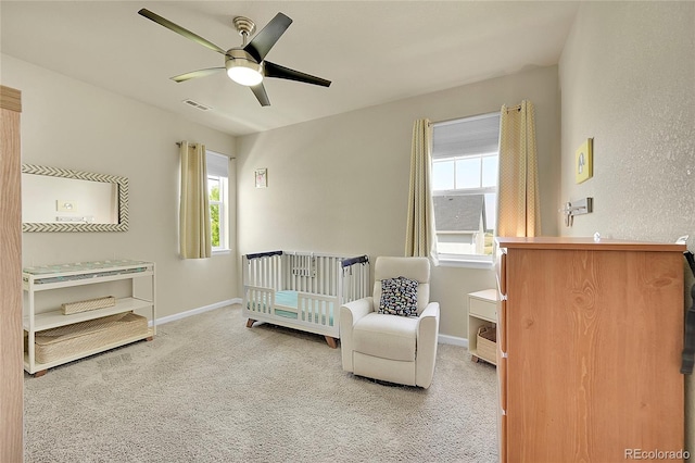 bedroom with multiple windows, light carpet, and a nursery area