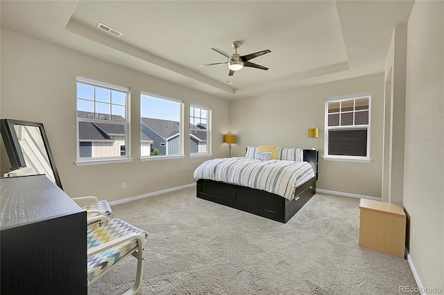 carpeted bedroom featuring ceiling fan and a tray ceiling