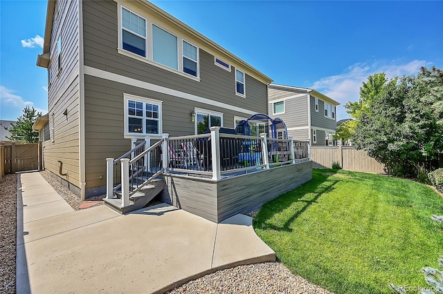 rear view of property with a patio, a deck, and a lawn