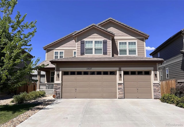 craftsman-style home with stone siding, an attached garage, and concrete driveway