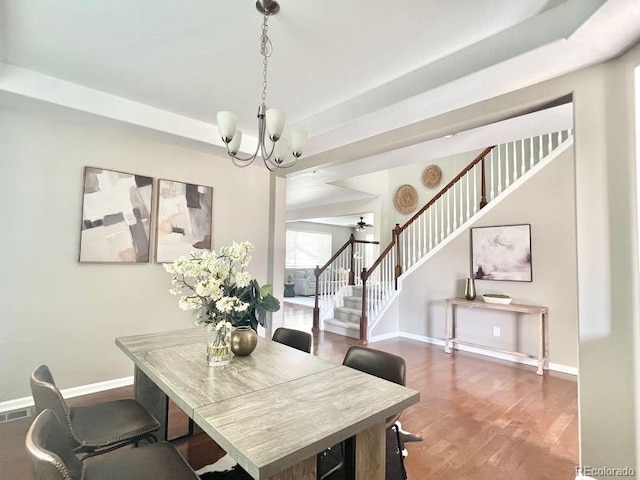 dining area featuring stairway, wood finished floors, baseboards, and a chandelier