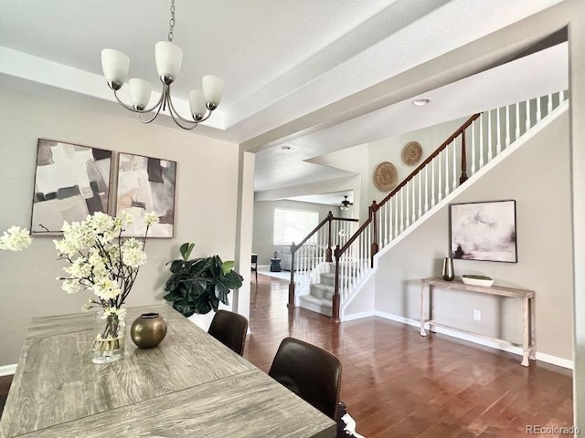 dining room featuring wood finished floors, stairway, baseboards, a raised ceiling, and a chandelier