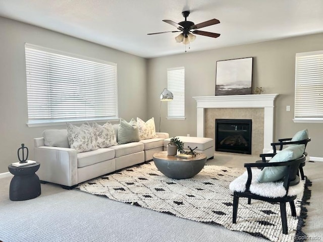 living area with baseboards, a tile fireplace, a wealth of natural light, and ceiling fan