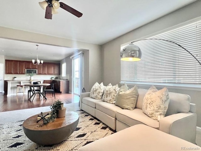 living room with ceiling fan with notable chandelier and wood finished floors