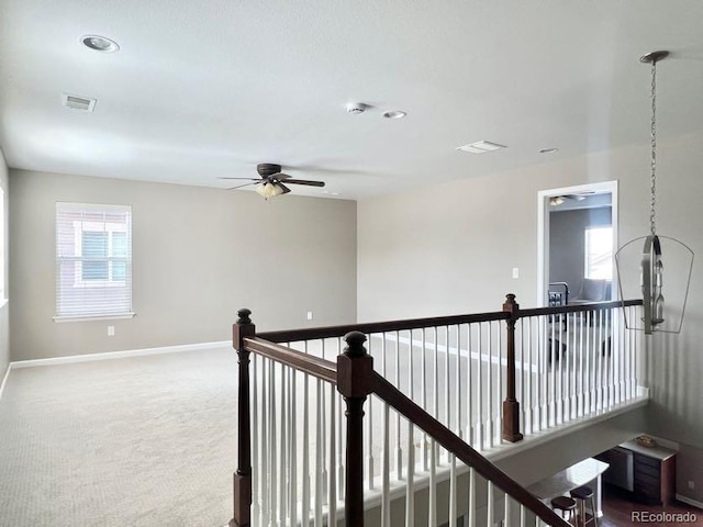 hallway featuring an upstairs landing, baseboards, visible vents, and dark carpet