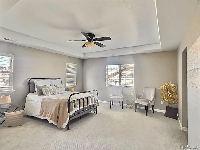 bedroom featuring light carpet, baseboards, and a tray ceiling