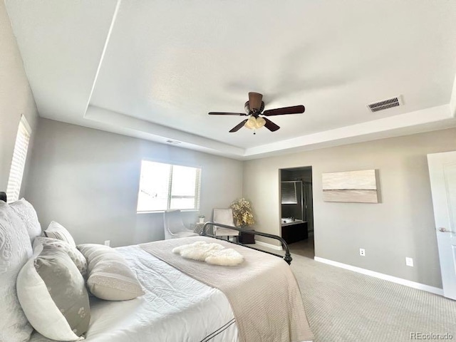 bedroom with a tray ceiling, baseboards, visible vents, and carpet flooring