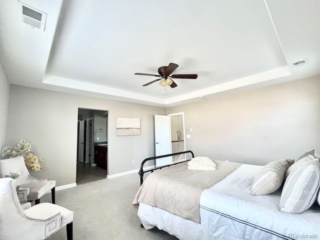 carpeted bedroom featuring a raised ceiling, baseboards, and visible vents