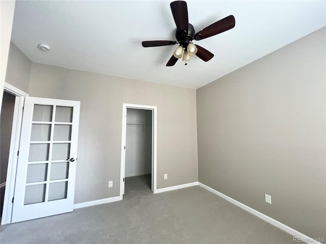 unfurnished bedroom with a closet, carpet floors, baseboards, ceiling fan, and a spacious closet