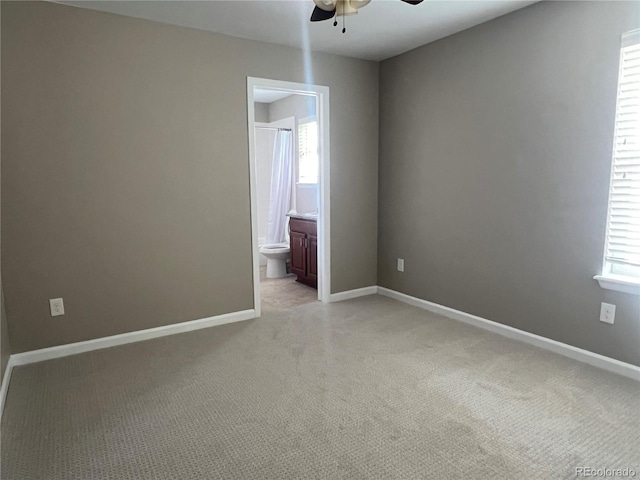 spare room featuring light colored carpet, baseboards, and ceiling fan